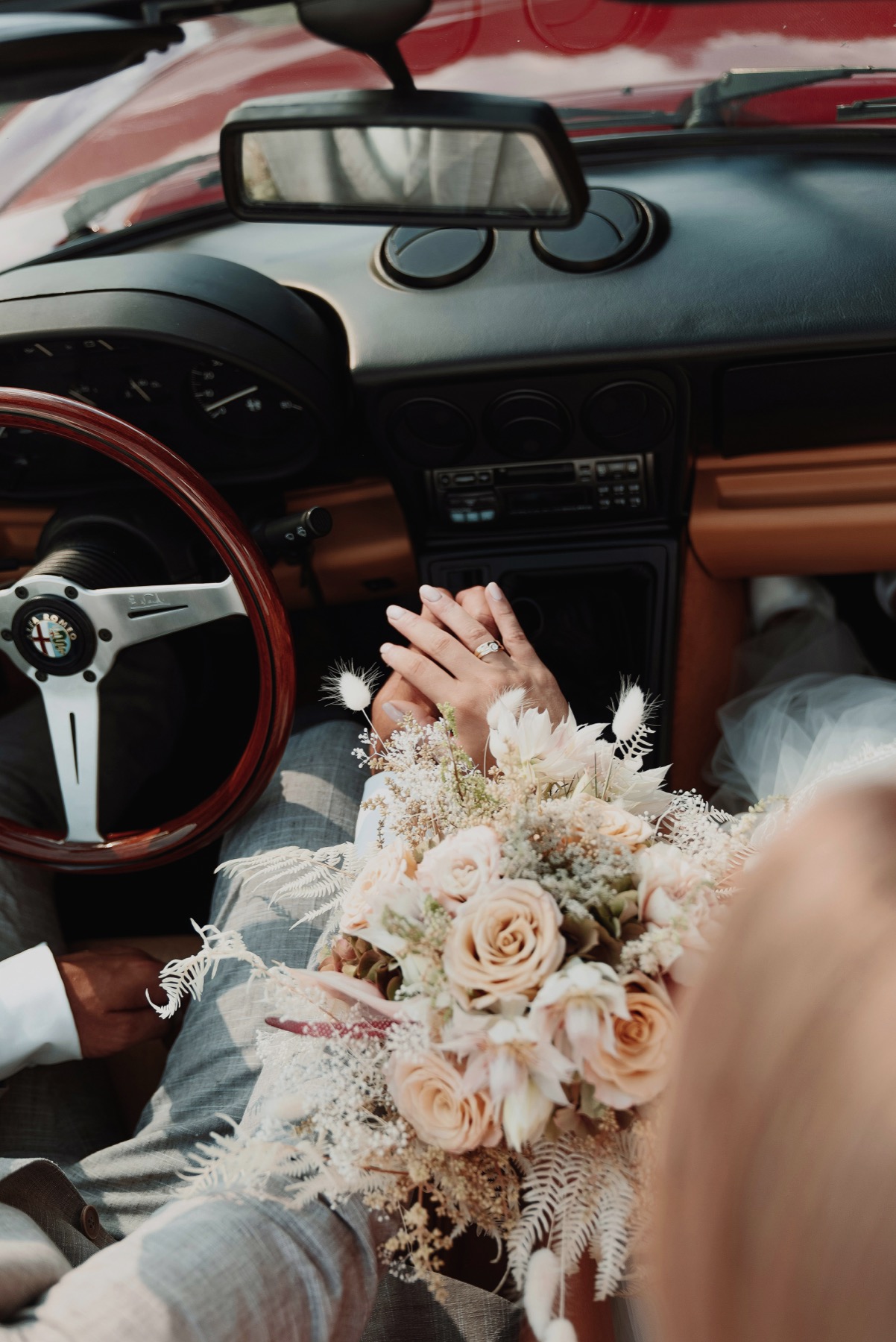 Casamento: mãos do casal e buquê no interior de um carro clássico: fotografia finalizada